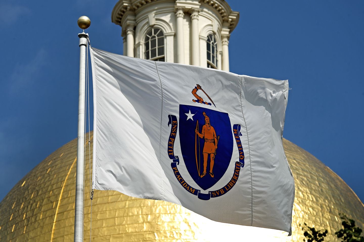 The Massachusetts state flag flies in front of the State House.