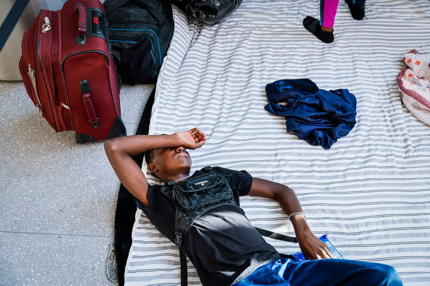Guivensly Joseph, 14, rested on his family’s makeshift bed after arriving at Logan International Airport, where the family would stay the night.