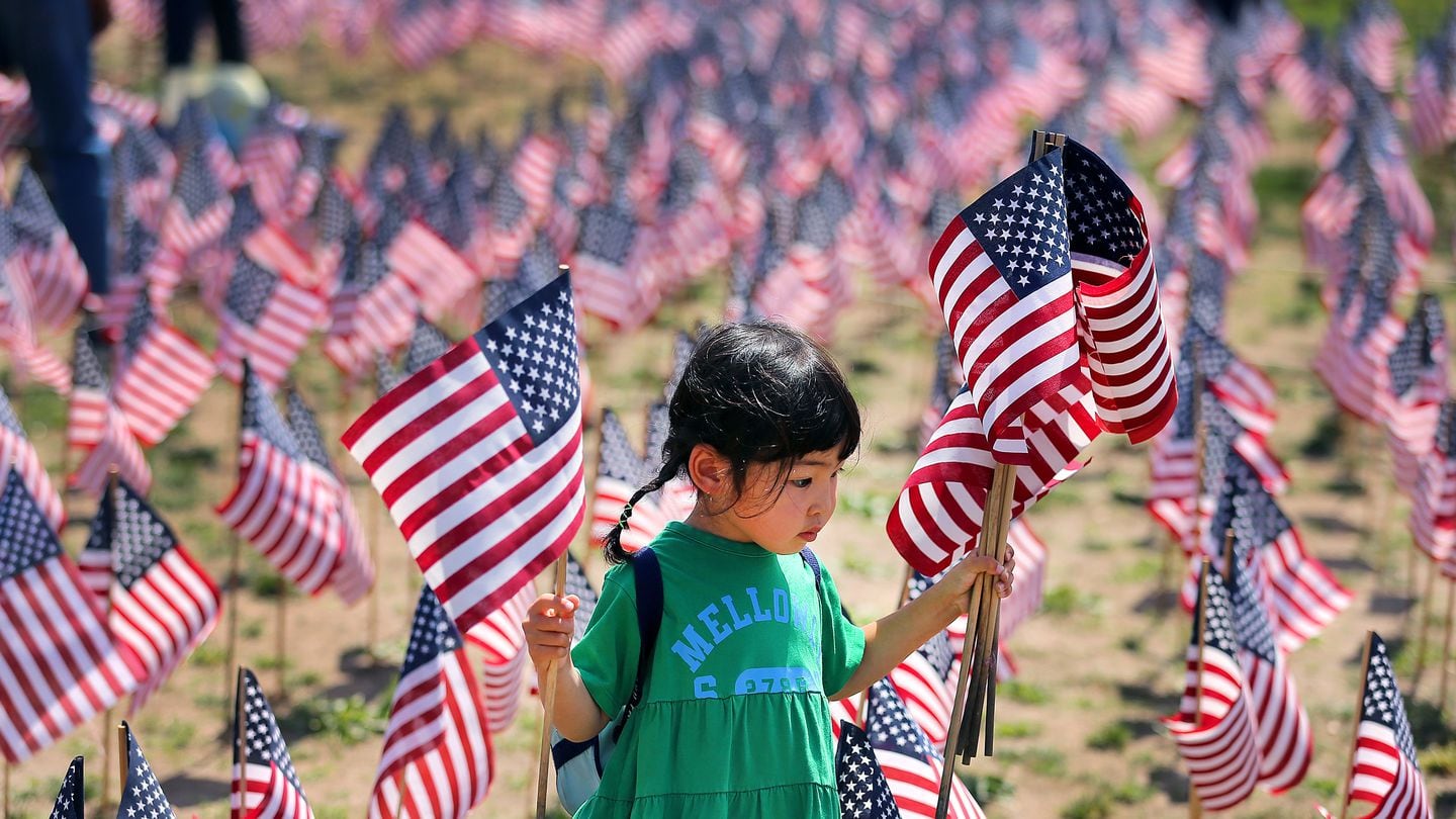 Boston -05/25/22  Volunteers began placing 37,400 American flags on Boston Common Wednesday morning to honor fallen Massachusetts service members since the Revolutionary War. Uta Uchida, 5 from Cambridge holds flags to be planted. This is the 13th annual Memorial Day flag garden. John Tlumacki/Globe Staff (metro)