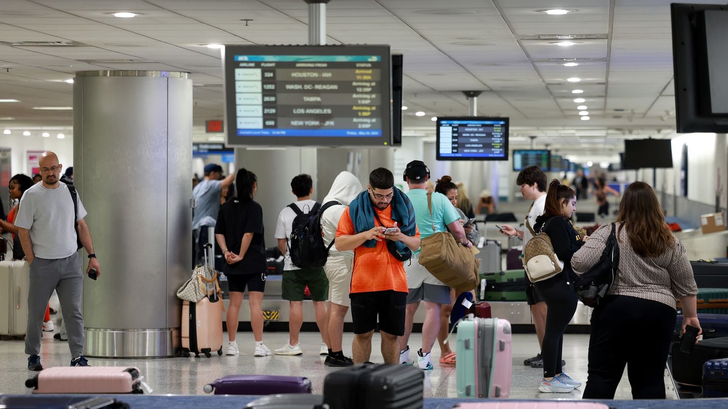 Travelers gather their luggage at baggage claim at the Miami International Airport on May 24 in Miami, Florida.